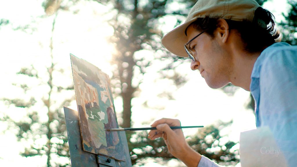 Young artist painting on an easel outdoors, surrounded by trees, with sunlight filtering through the leaves.