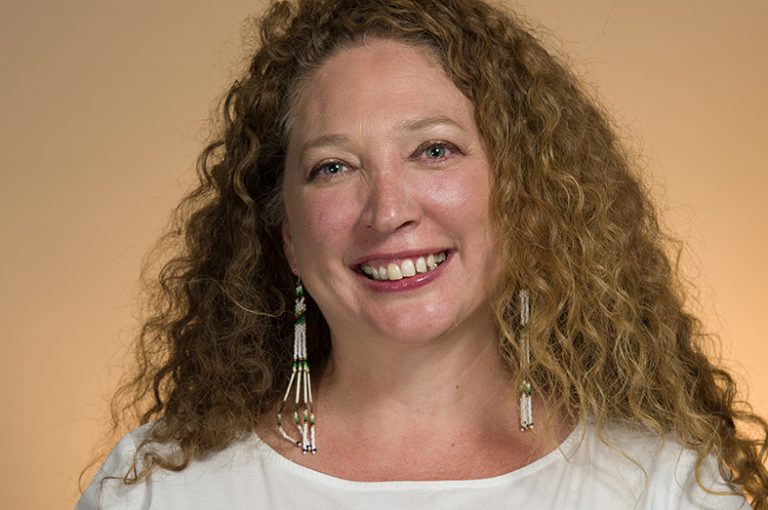 A smiling woman with curly hair posing for a photo