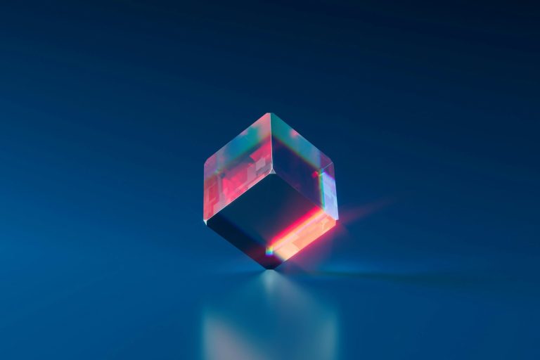 A translucent cube with vibrant colors, reflecting light against a smooth blue background.